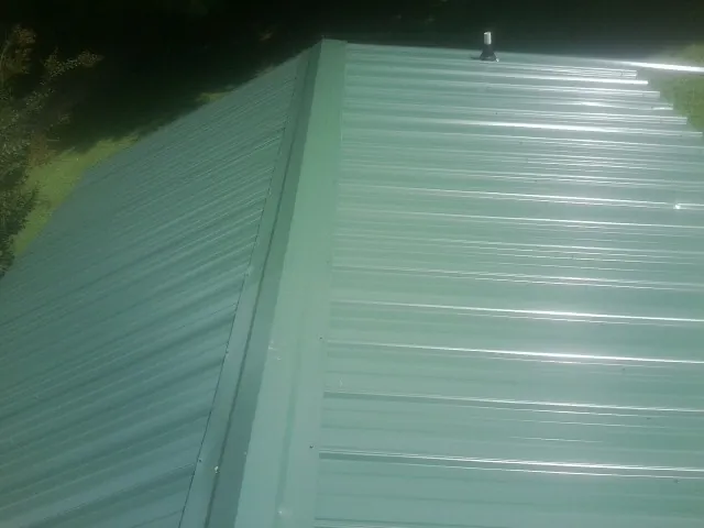 New green metal panels meeting at the ridge of a roof — Flat Roof Repair work by our crew in Underwood