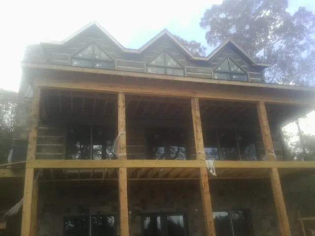 Dormers and porch framing on a large log home under construction — Roof Coating work by our crew in Underwood